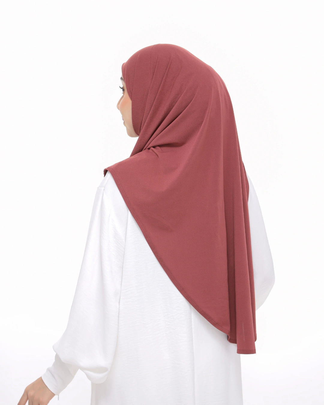 Woman wearing a dusty rose hijab with 'Safiya Sarung Moscrepe' branding.