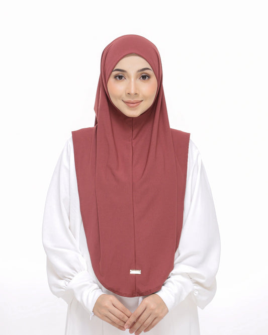 Woman wearing a dusty rose hijab with 'Safiya Sarung Moscrepe' branding.
